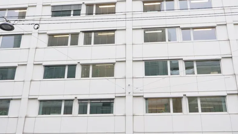 Ansicht der modernen Gebäudefassade mit vielen Fenstern und einem Geschäft im Erdgeschoss.