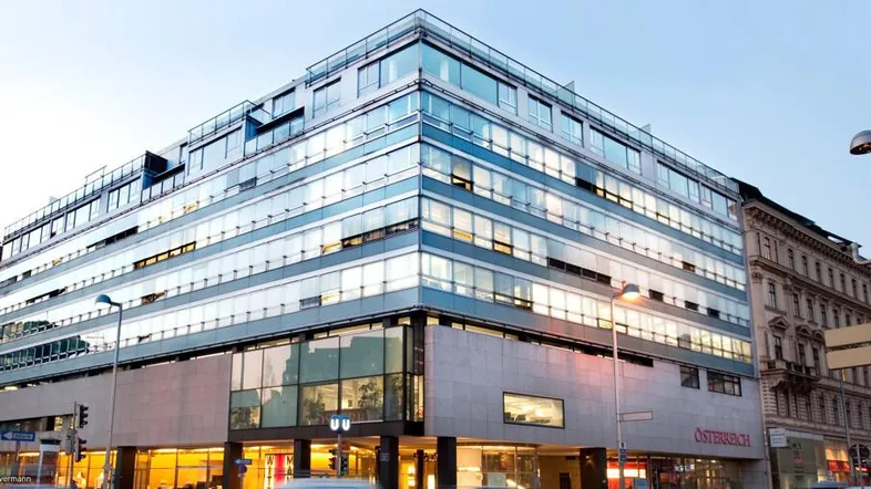 Modernes Bürogebäude mit Glasfassade und mehreren Etagen in einer städtischen Umgebung.