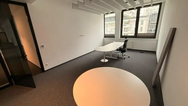 Modernes Einzelbüro mit Teppichboden, großen Fenstern und schallabsorbierenden Deckenpaneelen für eine ruhige Arbeitsatmosphäre.