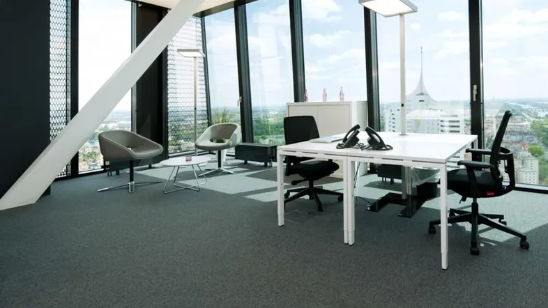 Modernes Büro mit großen Fenstern, Teppichboden und Panoramablick auf die Stadt und den Fluss.