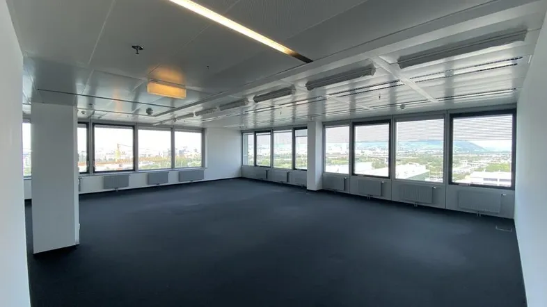 Großes, leeres Büro mit vielen Fenstern, die einen weiten Blick auf die Stadt bieten.