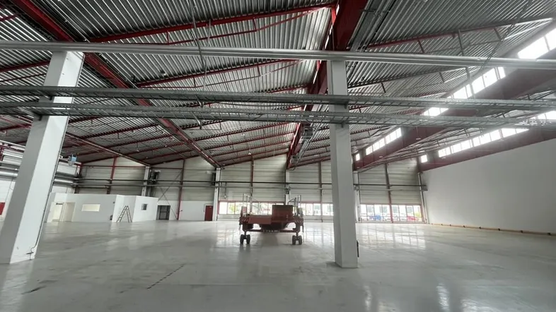 Geräumige Industriehalle mit hohen Decken, Betonboden und sichtbarer Metallkonstruktion, bereit zur Nutzung.