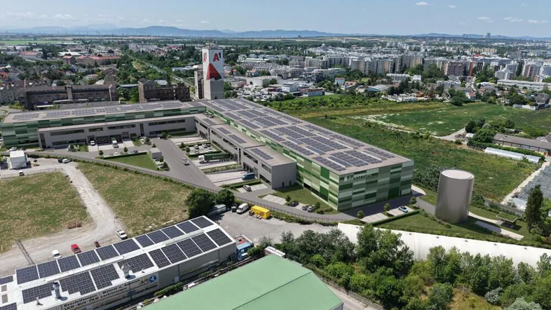 Luftaufnahme eines modernen Industrie- und Logistikkomplexes mit Solaranlagen auf den Dächern und städtischer Umgebung.