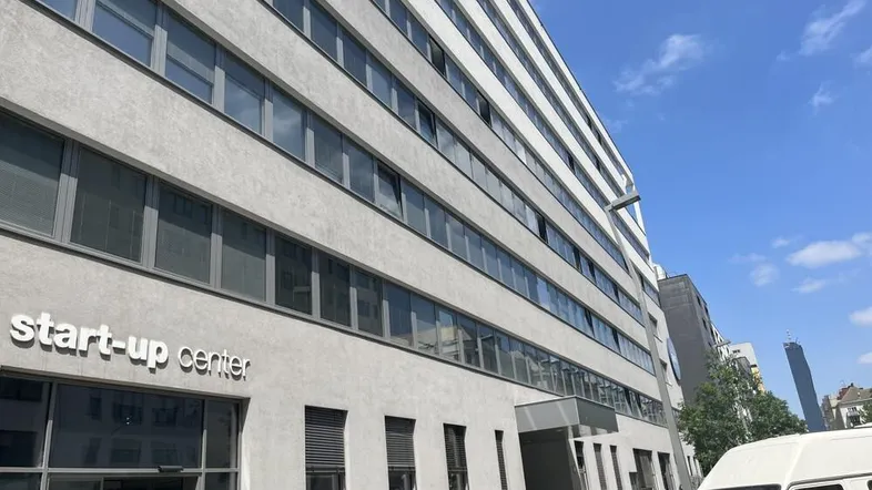 Modernes Bürogebäude mit "Start-up center" Beschriftung und vielen Fenstern unter blauem Himmel.