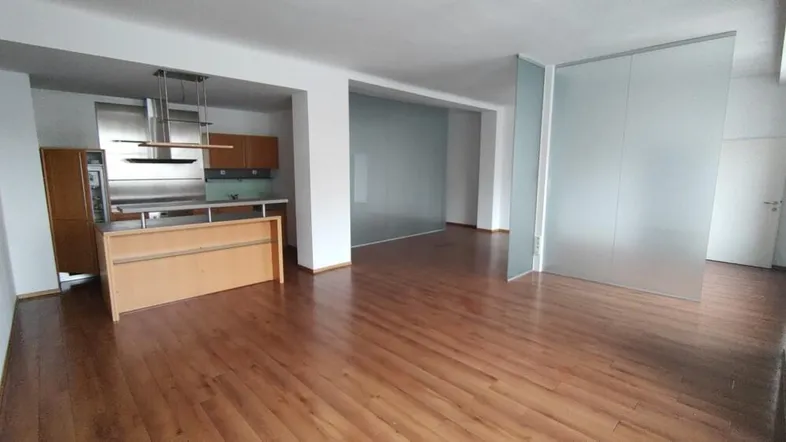 Offener Wohnbereich mit integrierter Küche, Holzboden und modernen Trennwänden aus Milchglas.