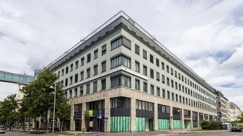 Modernes Büro- und Geschäftsgebäude an einer Straßenecke mit vielen Fenstern und einer markanten Architektur.
