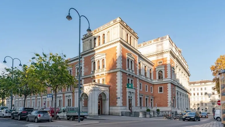 Historisches Gebäude mit roter Backsteinfassade und weißen Steinakzenten an einer belebten Straße.