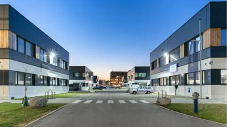 Moderne Geschäftsgebäude mit klaren Linien und großen Fenstern, umgeben von einer Zufahrtsstraße und Grünflächen.