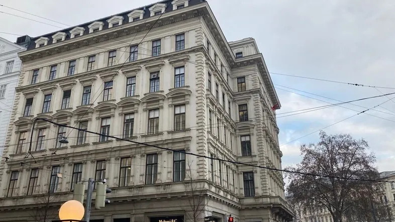 Historisches Gebäude mit klassischer Fassade und vielen Fenstern an einer belebten Straße.