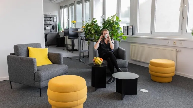 Gemütlicher Loungebereich in einem modernen Büro mit bequemen Sesseln und Pflanzen für entspannte Pausen.