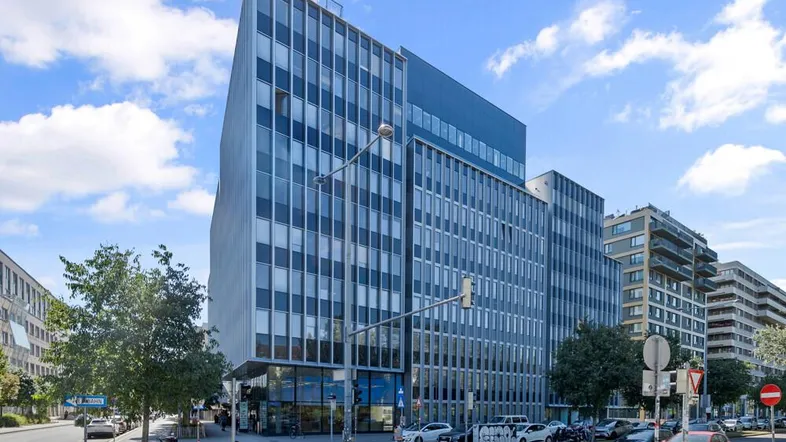 Modernes Bürogebäude mit Glasfassade und vielen Fenstern in städtischer Umgebung.