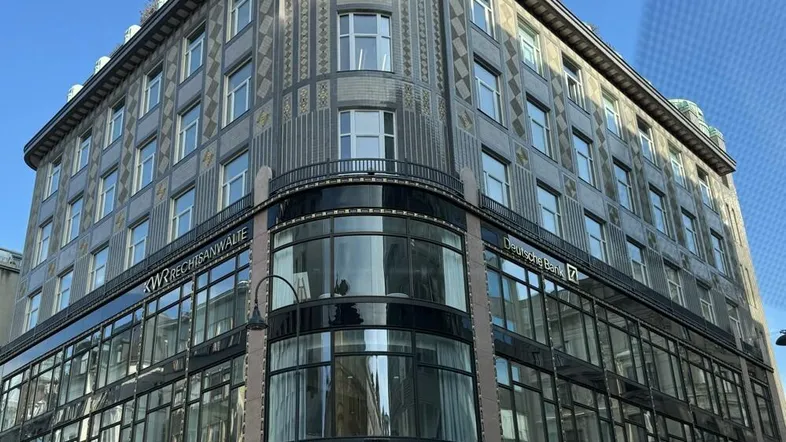 Historisches Eckgebäude mit markanter Architektur, Geschäften im Erdgeschoss und Büros darüber.