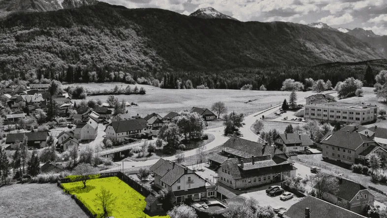 Luftaufnahme eines Grundstücks in ländlicher Umgebung mit Bergpanorama, das zum Verkauf steht.