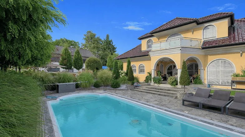 Großer Außenbereich mit Pool, Liegestühlen und einer Villa im mediterranen Stil.