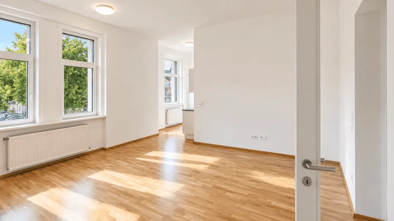 Helles Wohnzimmer mit Parkettboden, großen Fenstern und Blick ins Grüne.