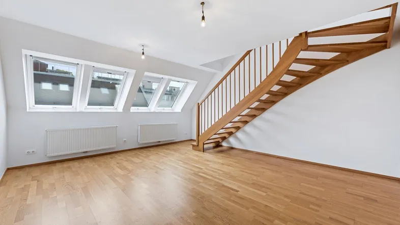 Helles Dachgeschosszimmer mit Holztreppe, Parkettboden und mehreren Dachfenstern für viel Tageslicht.