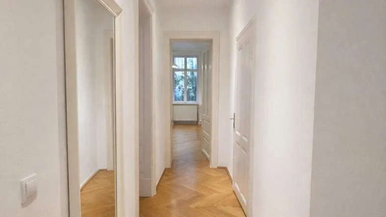 Heller Flur mit Fischgrätparkett und einem großen Wandspiegel, der den Raum optisch erweitert.