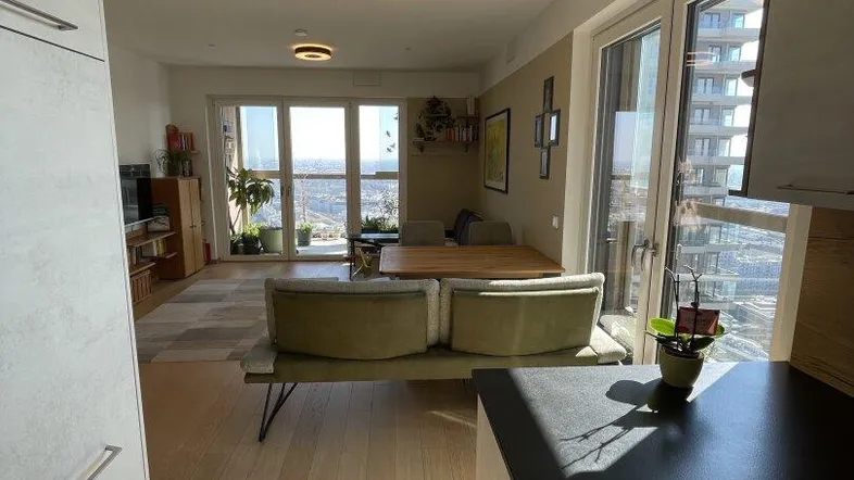 Heller Wohn-Essbereich mit offener Küche, Holzboden und weitem Stadtblick durch große Fenster.
