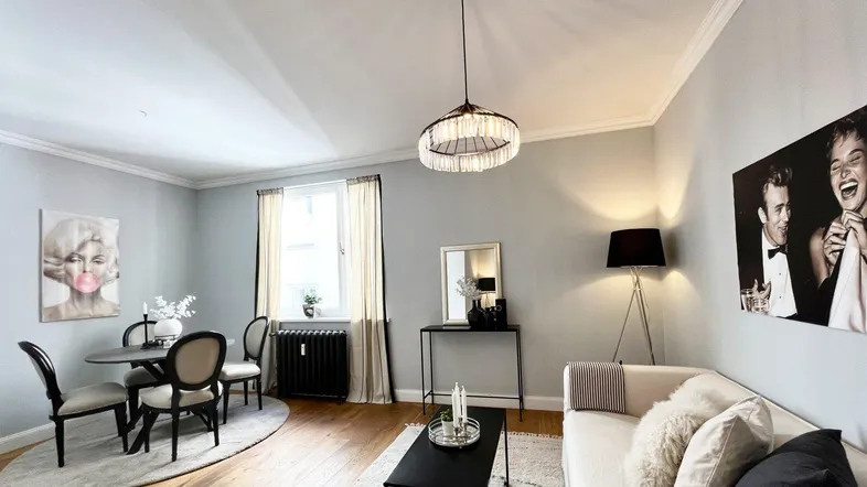 Helles Wohn- und Esszimmer mit Parkettboden, moderner Einrichtung und stilvollen Kunstwerken.