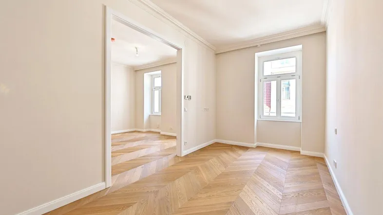 Helles Zimmer mit Fischgrätparkett und hohen Decken, bereit zur individuellen Gestaltung.