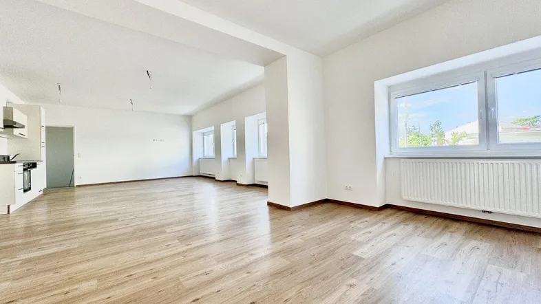 Geräumiger, heller Wohnbereich mit neuem Laminatboden und offener Gestaltung, ideal für individuelle Einrichtung.