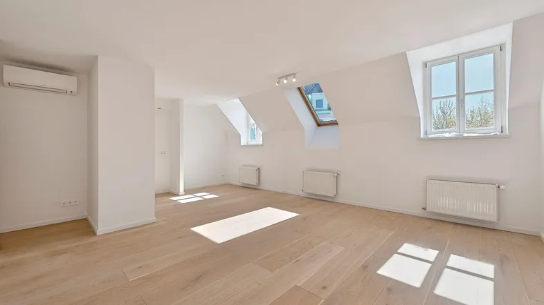Heller Dachgeschossraum mit Holzboden, Dachfenstern und Klimaanlage, ideal für flexible Nutzung.