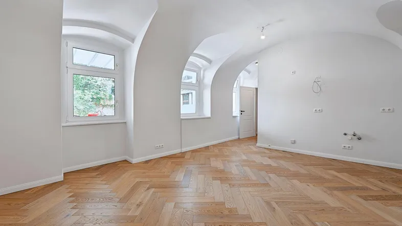 Helles Zimmer mit Fischgrätparkett und gewölbten Decken, bereit für die Einrichtung.