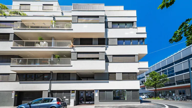 Modernes Wohngebäude mit mehreren Balkonen und großen Fenstern in städtischer Umgebung.