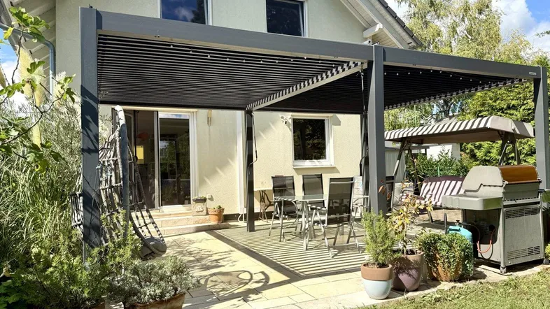 Geräumige Terrasse mit moderner Pergola, Essbereich und Grill, ideal für entspannte Stunden im Freien.