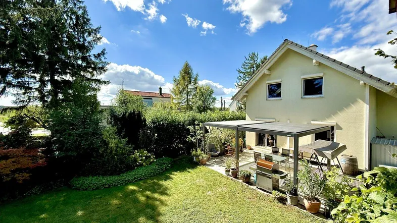 Großer, gepflegter Garten mit Rasenfläche und einer überdachten Terrasse am Haus.