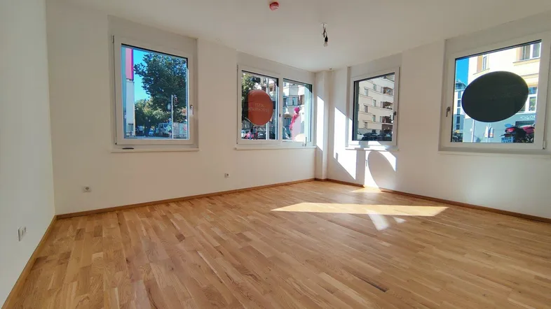 Helles Zimmer mit neuem Parkettboden und mehreren Fenstern, die viel Tageslicht hereinlassen.