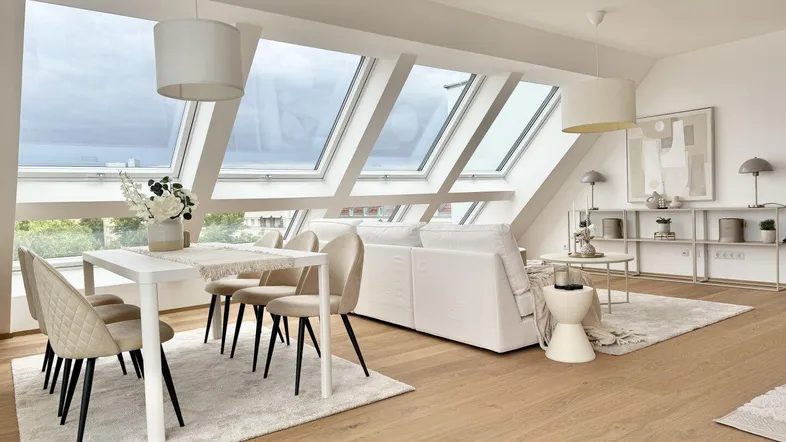 Heller Wohn- und Essbereich im Dachgeschoss mit großen Dachfenstern und modernem Design.