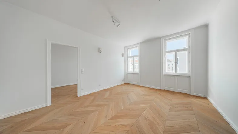 Helles, frisch renoviertes Zimmer mit Fischgrätparkett und weißen Wänden, bereit zur individuellen Gestaltung.
