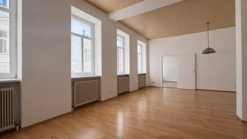 Helles und geräumiges Zimmer mit Holzdeckenverkleidung, Parkettboden und mehreren Fenstern.