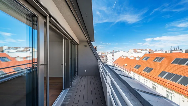 Geräumiger Balkon mit Holzboden und weitem Blick über die Dächer der Stadt.