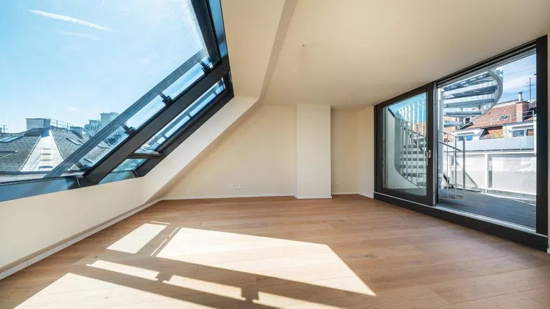Helles Dachgeschosszimmer mit großen Dachfenstern, Holzboden und Zugang zur Dachterrasse.
