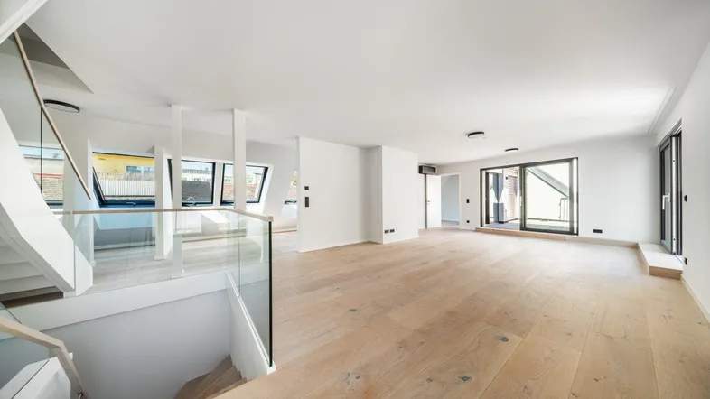 Offener Wohnbereich mit hellem Holzboden, moderner Treppe und viel natürlichem Licht.