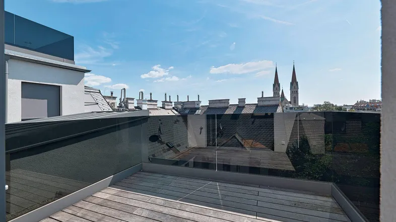 Dachterrasse mit Holzboden und Glasgeländer bietet einen weiten Blick über die Stadt und Kirchtürme.