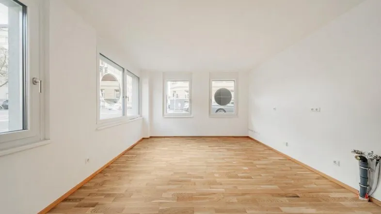 Heller, leerer Raum mit Parkettboden und großen Fenstern, bereit zur individuellen Gestaltung.