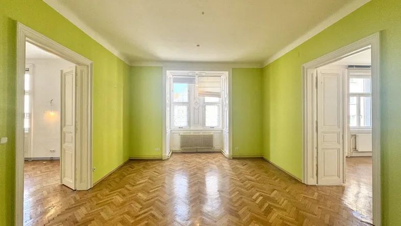 Geräumiges Zimmer mit Fischgrätparkett und hellgrünen Wänden, bereit für individuelle Gestaltung.