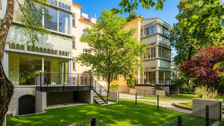 Gepflegter Gartenbereich mit Rasenflächen und Terrassen vor einem eleganten Gebäude.