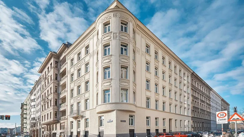 Elegantes Eckgebäude mit klassischer Architektur und vielen Fenstern in urbaner Umgebung.