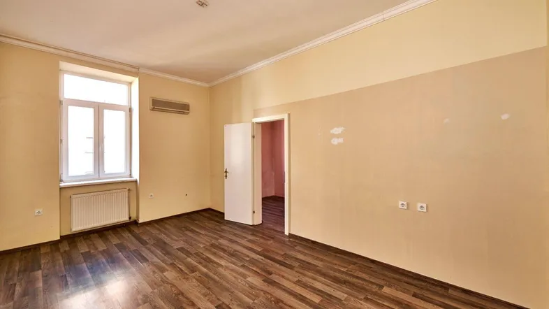 Helles, leeres Zimmer mit Laminatboden und Fenster, bereit zur individuellen Gestaltung.