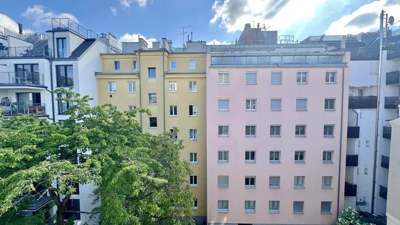 Mehrere Wohngebäude mit grünen Bäumen und blauem Himmel in einer städtischen Umgebung.