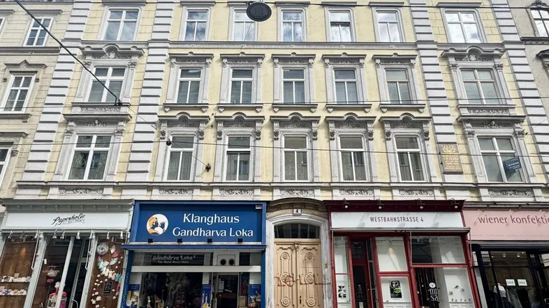 Historische Fassade eines Wiener Altbaus mit reich verzierten Fenstern und Geschäften im Erdgeschoss.