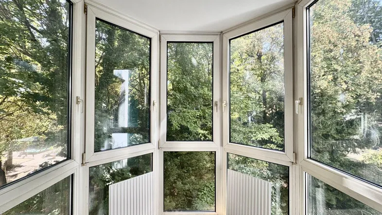 Heller Wintergarten mit großen Fenstern und Blick ins Grüne, ideal zum Entspannen.