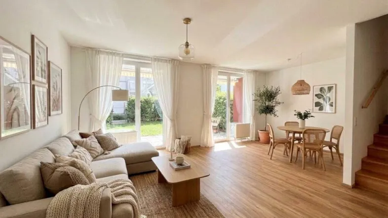Helles Wohn-Esszimmer mit beigem Sofa, Holzboden und Zugang zum Garten.