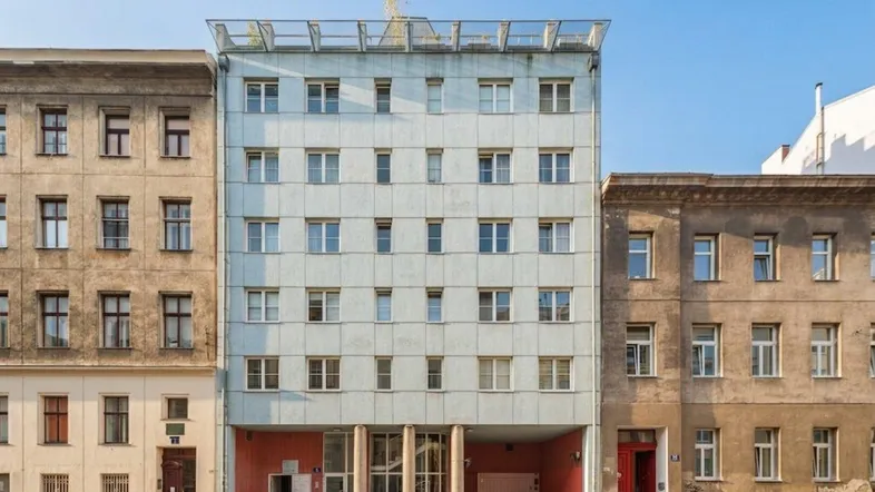Mehrstöckiges Wohngebäude mit vielen Fenstern und einem modernen Dachaufbau in städtischer Umgebung.