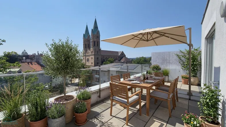 Große Dachterrasse mit Esstisch, Sonnenschirm und Blick auf die Stadtkirche unter blauem Himmel.