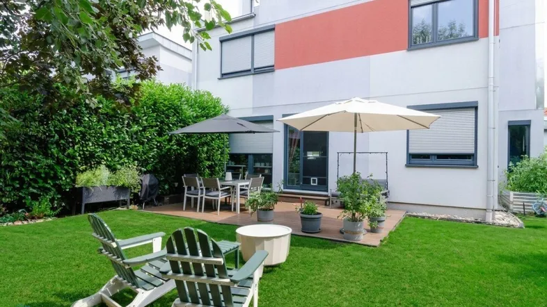 Große Terrasse mit Gartenmöbeln, Sonnenschirmen und angrenzendem gepflegten Rasenbereich.